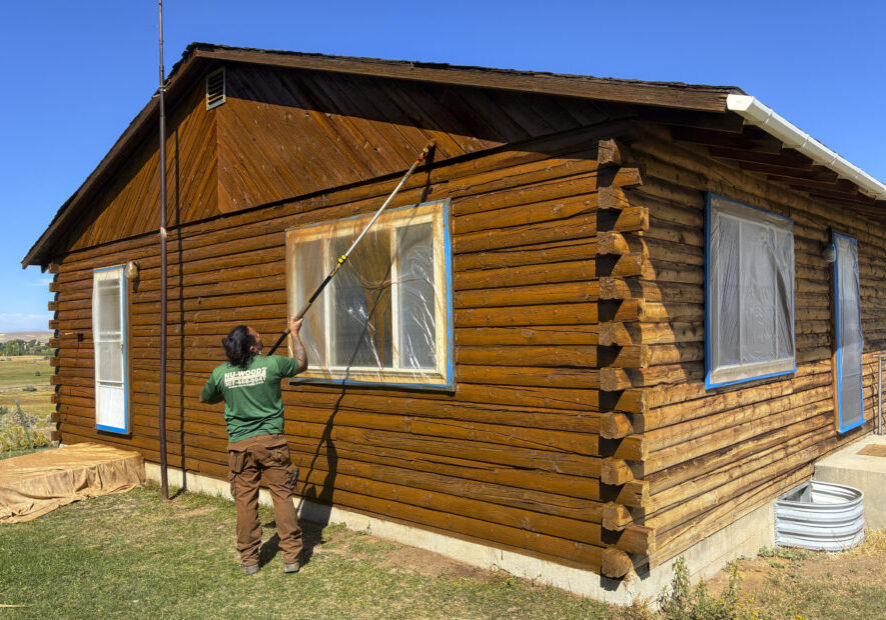Employee Staining A Log Cabin